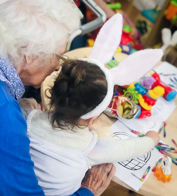 Care home resident and little girl enjoying Easter crafts 