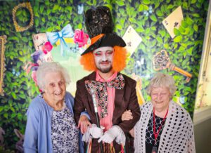 Two care home residents next to Manager Daniel Sabau dressed as The Mad Hatter.