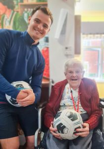 Cardinals in the Community member with a resident holding a football.