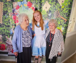 Lucy dressed as Alice with two residents at the Mad Hatter's Tea Party. 