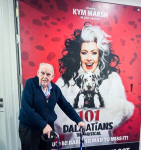 A resident at the theatre with the promotional poster in the background.