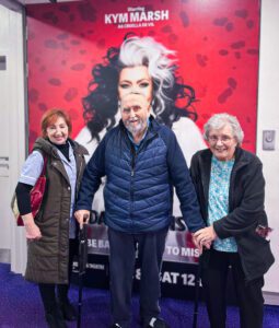 Residents and a staff member at the theatre with the promotional poster in the background.