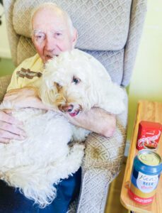 Jazz the dog cuddling with a resident.