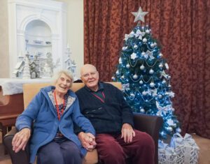 Two Lawn residents sat infront of a Christmas tree. 