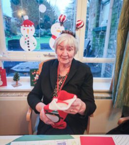A resident smiling at the camera whilst holding a stocking. 