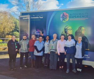 Staff and relatives standing next to the Dementia Virtual Tour bus. 