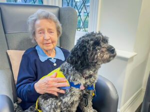 2025 March highlights: A resident from our Luton care home with a Pets as Therapy dog on her lap.