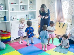 Musical Bumps leader playing games with visiting children at Little Bramingham Farm. The children are jumping and playing around her.