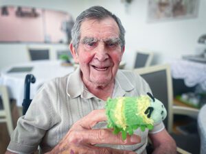 A Luton care home resident with a green stripey finger puppet on his finger, which he used during games with the children.