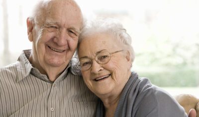 Older Man and Woman Sitting on a couch smiling.