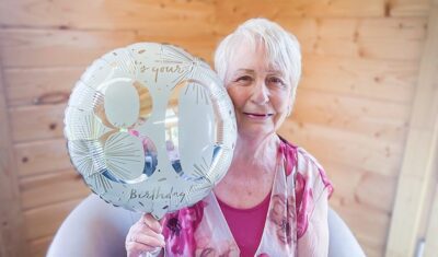 Marion on her birthday holding an 80th balloon.