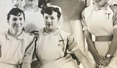An old black and white photo of Jill when she was a nurse, sat with other nurses.