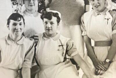 An old black and white photo of Jill when she was a nurse, sat with other nurses.