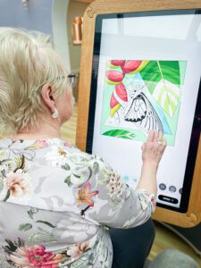 Marion using a large digital tablet to play a game.