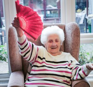 New Copford Place care home resident dancing with a red fan.
