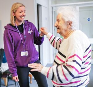 Libb and New Copford Place care home resident Pat dance together smiling.