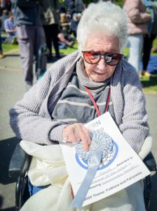 A Friends of the Elderly Malvern resident holding the certificate and rosette.