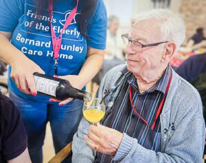 A resident receiving a drinks top-up from a member of staff.