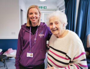 Libb and New Copford Place care home resident arm in arm smiling at the camera. 