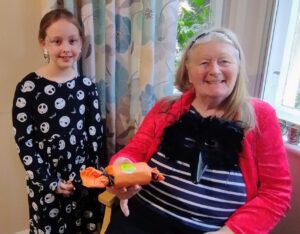 Lillie-Griffiths-giving-Malvern-Day-Care-Client-Gwen-Farrer-her-hand-made-Halloween-Cracker.